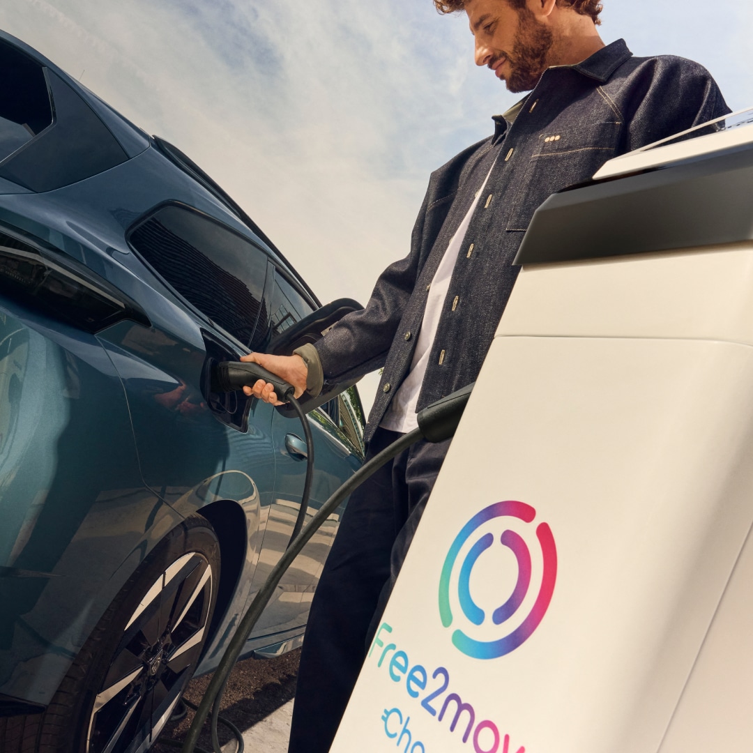 Man charging a PEUGEOT E-308 SW at a Free2move Charge charging station